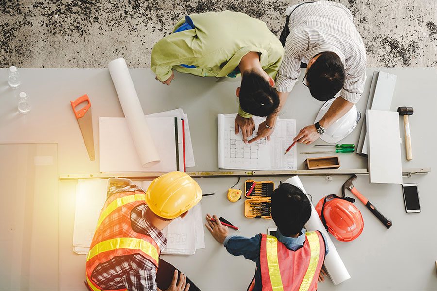 Business Insurance - View from Above of a Group of Engineers and Contractors Working on New Building Blueprints on a Table